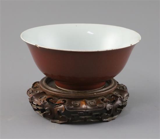 A Chinese copper red glazed bowl, Qianlong seal mark and of the period (1736-95), D. 18.2cm, small rim chips, wood stand